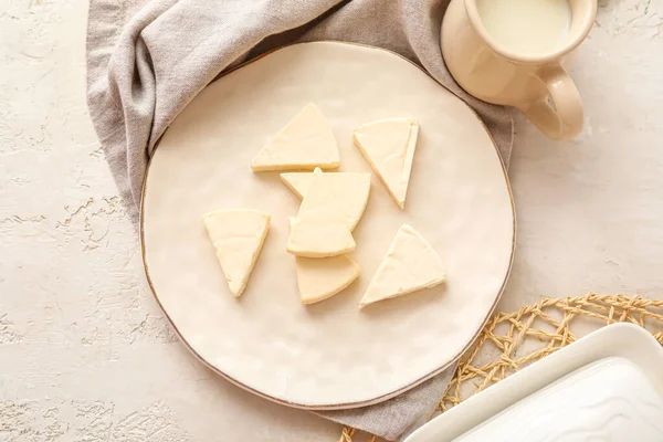 Açık arkaplanda lezzetli işlenmiş peynir ve süt üçgenleri olan bir tabak.