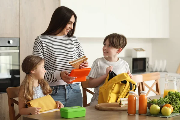Anne küçük çocukları için mutfakta öğle yemeği hazırlıyor.