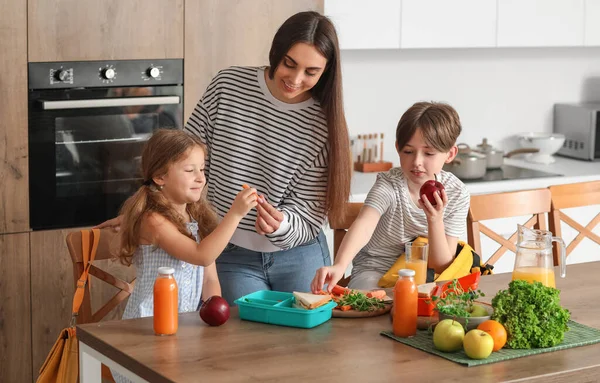 Anne küçük çocukları için mutfakta öğle yemeği hazırlıyor.