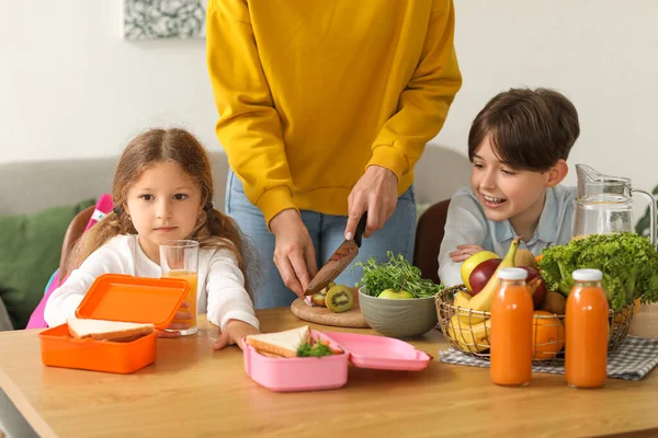 Anne, küçük çocuklarına mutfakta öğle yemeği hazırlıyor.