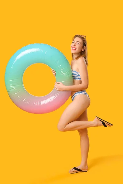 若いです女性で水着でインフレータブルリング上の黄色の背景 — ストック写真