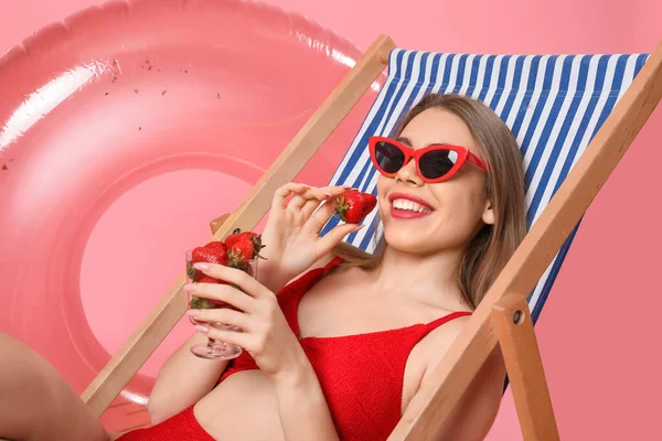 Young Woman Beach Accessories Eating Strawberries Deck Chair Pink Background — Stock Photo, Image