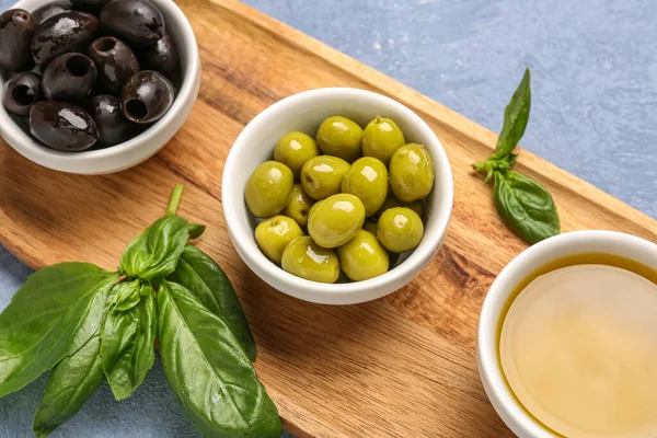 Olgun zeytinli kaseler ve mavi arka planda yağlar