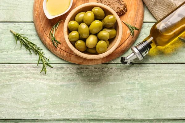 Schüssel Mit Reifen Oliven Und Einer Flasche Auf Grünem Holzgrund — Stockfoto