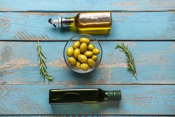 Schüssel Mit Reifen Oliven Und Ölflaschen Auf Blauem Holzhintergrund — Stockfoto