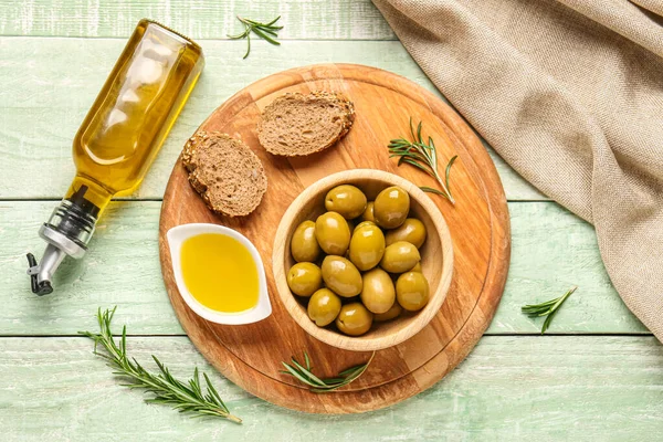 Reife Oliven Brot Schalen Und Eine Flasche Auf Grünem Holzgrund — Stockfoto