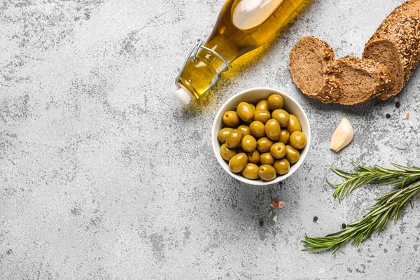 Stock image Bowl with ripe olives, bread and bottle of oil on light background