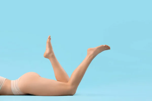 Young woman with cellulite problem lying on blue background