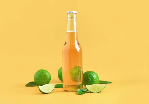 黄色の背景にライムと冷たいビールのボトル — ストック写真