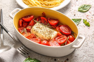 Domatesli fırın tabağı ve gri arka planda beyaz peynir.