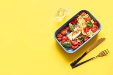 Domatesli lezzetli makarna ve sarı arka planda beyaz peynir.