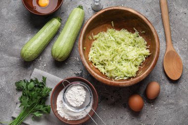 Rendelenmiş kabak ve gri arka planda börek hazırlamak için malzemelerle dolu bir kase.