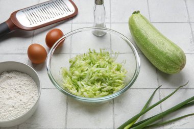 Beyaz fayanslı börek hazırlamak için rendelenmiş kabak ve malzemeyle dolu bir kase.