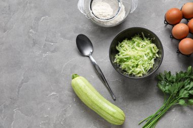 Rendelenmiş kabak ve gri arka planda börek hazırlamak için malzemelerle dolu bir kase.