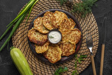 Siyah arka planda ekşi kremalı bir tabak lezzetli kabaklı börek.