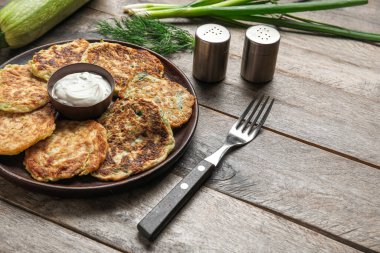 Ahşap arka planda ekşi kremalı bir tabak lezzetli kabaklı börek.
