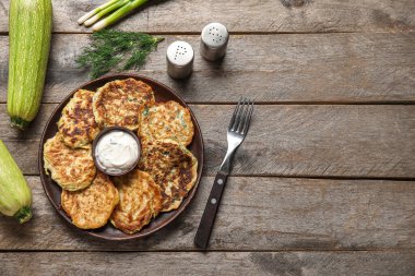 Ahşap arka planda ekşi kremalı bir tabak lezzetli kabaklı börek.