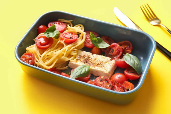 stock image Baking dish of tasty pasta with tomatoes and feta cheese on yellow background