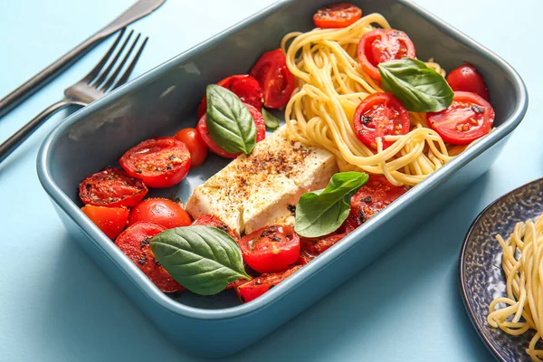 stock image Baking dish of tasty pasta with tomatoes and feta cheese on blue background