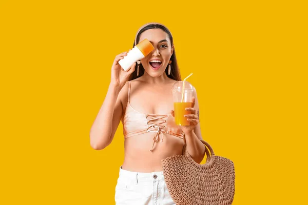 Junge Frau Mit Sonnencreme Saft Und Strandtasche Auf Gelbem Hintergrund — Stockfoto