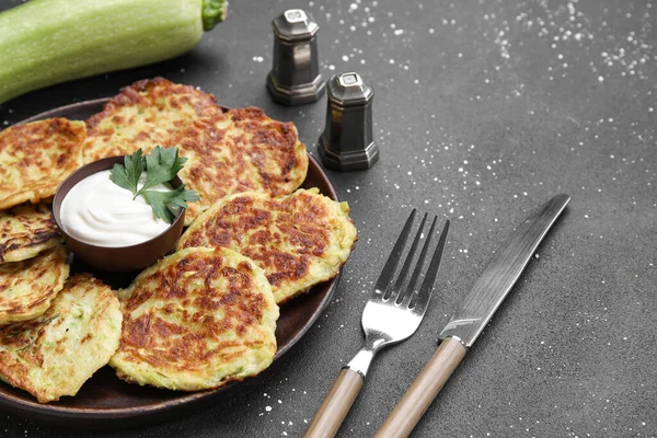 stock image Plate with tasty zucchini fritters on grunge background