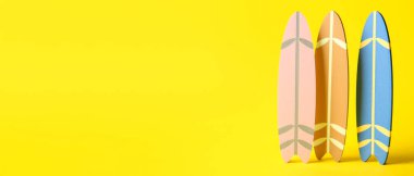 Sarı arkaplanda küçük sörf tahtaları ve metin için boşluk