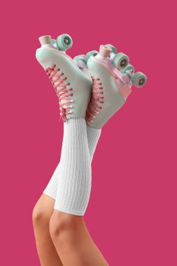 Pembe arka planda paten giyen genç kadınların bacakları.