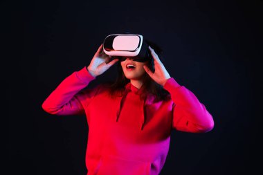 Pretty young woman in VR glasses on black background