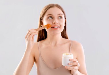 Yüzüne şekerleme yapıştırıcısı süren genç bir kadın.