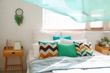 Yatak odası, yatak odası, komodin ve beyaz duvarda asılı düş kapanı.