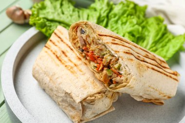 Yeşil ahşap arka planda marullu lezzetli bir shawarma tabağı.