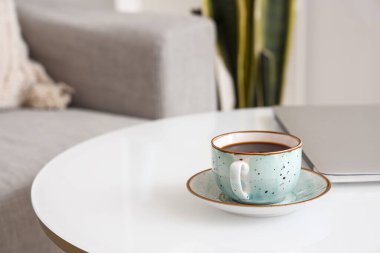 Bir fincan lezzetli kahve ve modern dizüstü bilgisayar masada, yakın plan.