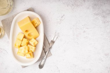 Beyaz masanın üzerinde İsviçre peyniri parçaları olan bir tabak.