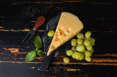 Koyu ahşap arka planda lezzetli İsviçre peyniri olan tahta.