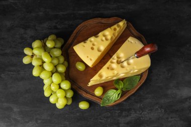 Lezzetli İsviçre peyniri ve siyah arka planda üzümlü tahta