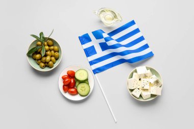 Yunanistan bayrağı ve beyaz zemin üzerinde beyaz peynir, zeytin, salatalık ve domates tabakları