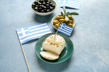 Mavi grunge masasında mozarella peyniri, zeytin ve Yunanistan bayrakları bulunan tabaklar