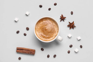 Gri arka planda bir fincan sıcak espresso, şeker, anason ve kahve çekirdeği.