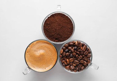 Bir fincan sıcak espresso ve beyaz arka planda kahve çekirdekleri.