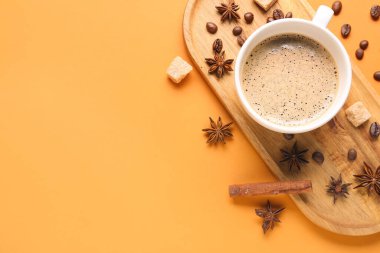 Bir fincan sıcak espresso ve turuncu arka planda kahve çekirdekleri.