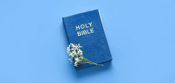 Holy Bible and flowers on blue background