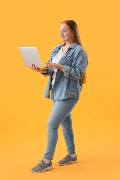 在黄色背景下使用笔记本电脑的女程序员 — 图库照片