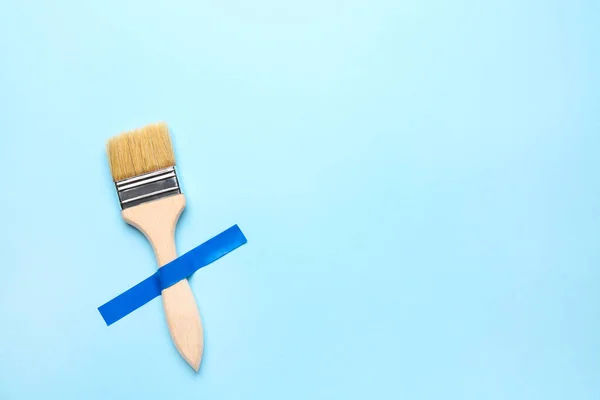 Paint brush with adhesive tape on blue background