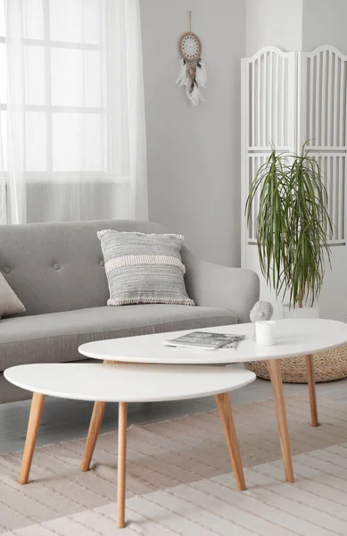 stock image Interior of modern living room with sofa, coffee table and dream catcher hanging on light wall