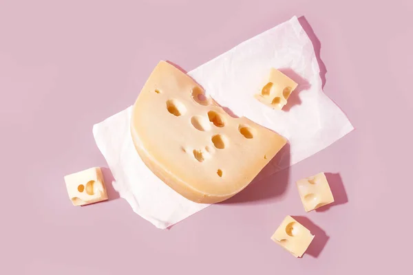Papel Manteiga Com Pedaços Queijo Suíço Sobre Fundo Rosa — Fotografia de Stock