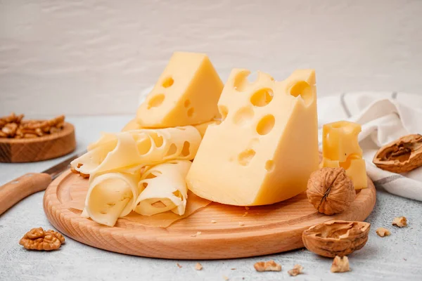 stock image Board with pieces of Swiss cheese and walnut on white table