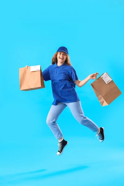 ジャンプ女性宅配便で紙袋で青の背景 — ストック写真