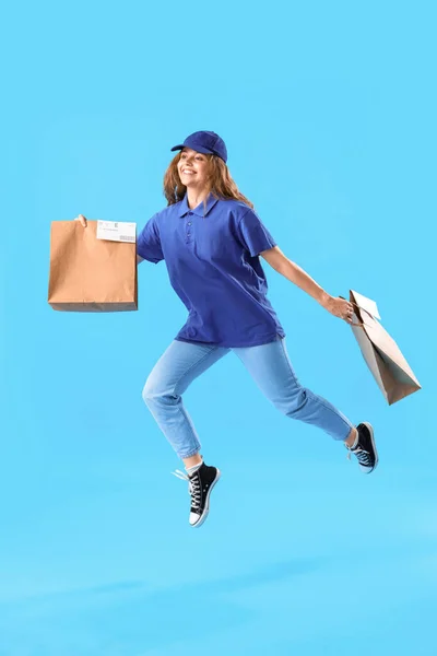 ジャンプ女性宅配便で紙袋で青の背景 — ストック写真