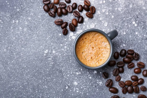 灰色の背景にホットエスプレッソとコーヒー豆のカップ — ストック写真