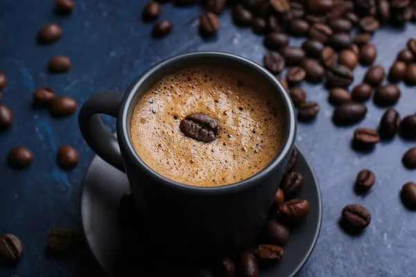 stock image Cup of hot espresso and coffee beans on blue background